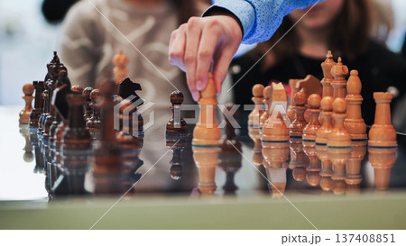 Hand moving a chess piece, reflecting strategy and competition on a board game 137408851