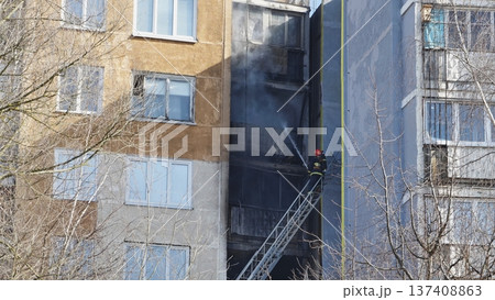 Firefighter climbing ladder and extinguishing fire on apartment balcony Firefighter climbing ladder and extinguishing fire on apartment balcony 137408863