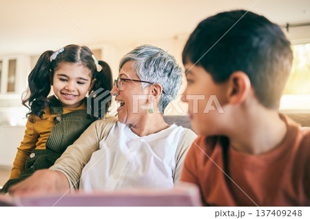 Happy kids, smile or grandma reading a book for learning, education or storytelling on sofa at home. Family, senior or grandmother with children siblings for a fantasy story to enjoy bonding together 137409248