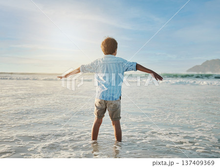 Freedom, fun and child in waves at beach, playful on tropical summer holiday in Australia with blue sky. Ocean, adventure and sun, back of boy in water and playing with energy on island vacation Freedom, fun and child in waves at beach, playful on tropical summer holiday in Australia with blue sky. Ocean, adventure and sun, back of boy in water and playing with energy on island vacation 137409369