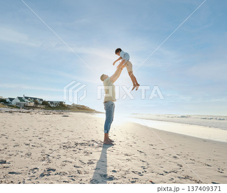 Father throwing child in air on beach, sunshine and playing together in summer on tropical island holiday. Fun, dad and boy on happy ocean vacation with love, support and relax in blue sky in Hawaii. 137409371
