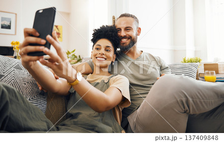 Interracial couple, selfie and happy on couch, relax at home with social media, streaming and memory with commitment. Smile in picture, post and love, care and trust, people in lounge with romance Interracial couple, selfie and happy on couch, relax at home with social media, streaming and memory with commitment. Smile in picture, post and love, care and trust, people in lounge with romance 137409848