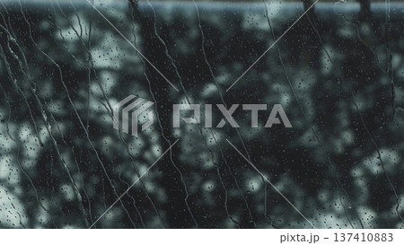 Rain drops streaming down a glass window during a dark day 137410883