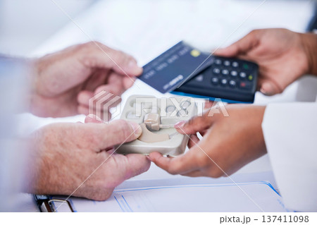 Doctor, hands and patient with credit card in payment for hearing aid, sound or consultation at clinic. Closeup of person paying on pos or electronic machine for ear device in audiology at hospital Doctor, hands and patient with credit card in payment for hearing aid, sound or consultation at clinic. Closeup of person paying on pos or electronic machine for ear device in audiology at hospital 137411098