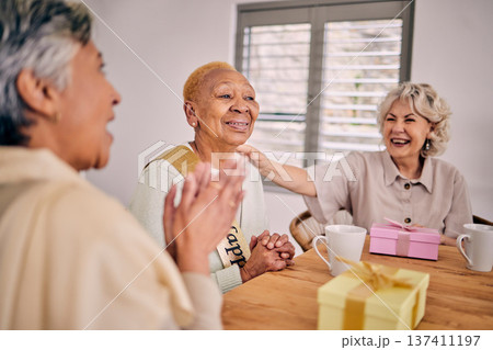 Senior friends, birthday singing and party at a home with a present and gift with excited people. Surprise, celebration and retirement of elderly group at a dining room table together with a smile 137411197