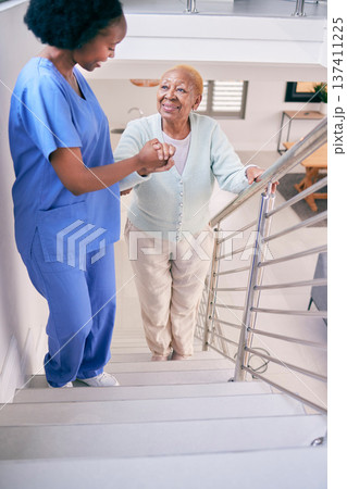 Caregiver, stairs and elderly woman holding hands, help and assistance in home. Nurse, steps and senior African patient walking up, support of person with a disability and happiness in healthcare 137411225