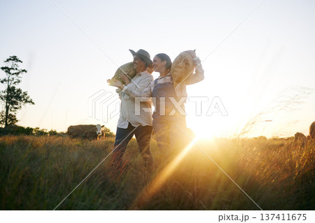 Farm harvest, women walking and countryside with a smile from working on a grass field with grain bag. Sustainability, eco friendly and agriculture outdoor at sunset in nature with farmer management Farm harvest, women walking and countryside with a smile from working on a grass field with grain bag. Sustainability, eco friendly and agriculture outdoor at sunset in nature with farmer management 137411675