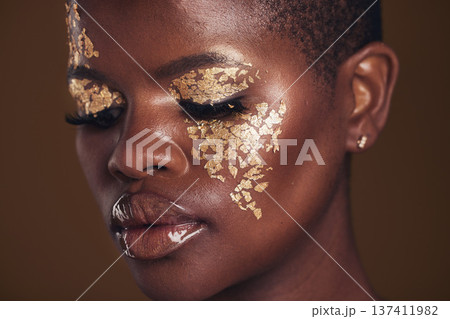 Gold, creative and black woman with makeup for beauty aesthetics isolated in a studio brown background eyes closed. Art, luxury and face of African person with cosmetic glamour or design for skincare 137411982