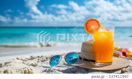 A glass of red drink with a straw and a straw hat on the beach. The drink is a refreshing beverage to enjoy on a hot day at the beach A glass of red drink with a straw and a straw hat on the beach. The drink is a refreshing beverage to enjoy on a hot day at the beach 137411997
