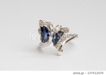 A women's piece of jewelry made of white gold, diamonds, and sapphires in the shape of a butterfly on a white background. A women's piece of jewelry made of white gold, diamonds, and sapphires in the shape of a butterfly on a white background. 137412070