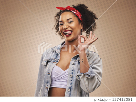Woman, ok sign and studio portrait with smile, tongue and funny face for good review by brown background. African girl, student or fashion model with hand for icon, vote or feedback with comic laugh 137412081