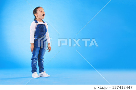Shock, surprise and girl child in a studio with mockup space for advertising, promotion or marketing. Wow, wtf and full length of a kid model with omg face expression by blue background with mock up. Shock, surprise and girl child in a studio with mockup space for advertising, promotion or marketing. Wow, wtf and full length of a kid model with omg face expression by blue background with mock up. 137412447