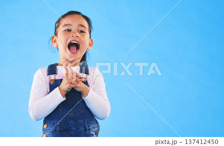 Excited, youth and a child on a blue background with mockup for information. Playful, freedom and a young girl kid or model playing with happiness on a studio background with space for creativity Excited, youth and a child on a blue background with mockup for information. Playful, freedom and a young girl kid or model playing with happiness on a studio background with space for creativity 137412450