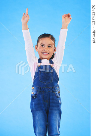 Success, girl child and champion, winner and achievement with happiness and excited isolated on blue background. Cheers, yes and winning with celebration, pride and happy kid with arms up in a studio 137412470
