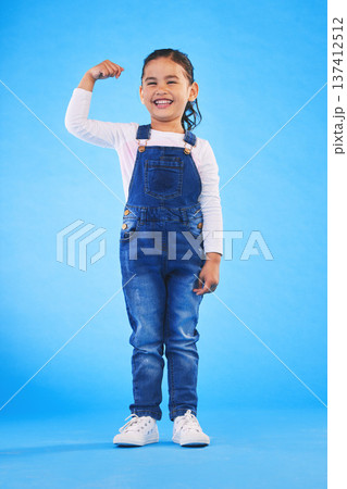 Young, girl child and champion, winner and emoji with happiness, strong and excited isolated on blue background. Power, muscle and winning with success, body language and happy kid in a studio Young, girl child and champion, winner and emoji with happiness, strong and excited isolated on blue background. Power, muscle and winning with success, body language and happy kid in a studio 137412512