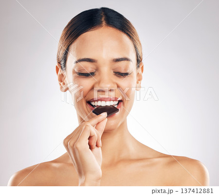 Woman, eating chocolate and thinking of diet for skincare, beauty and inner health on white background. Young person or model with cacao product, food or candy for skin care or dermatology in studio 137412881