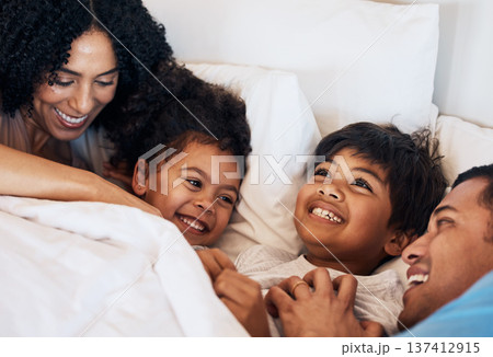 Family, funny and children laughing in bed at home in the morning together with their happy parents. Relax, love or smile with a mother, father and kids lying in a bedroom for weekend bonding 137412915