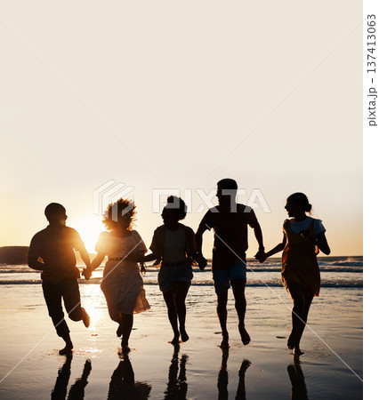 Silhouette, summer and friends holding hands at sunset beach for fun and travel. Banner space, men and women group running outdoor in water with love, support and happiness on vacation or holiday Silhouette, summer and friends holding hands at sunset beach for fun and travel. Banner space, men and women group running outdoor in water with love, support and happiness on vacation or holiday 137413063