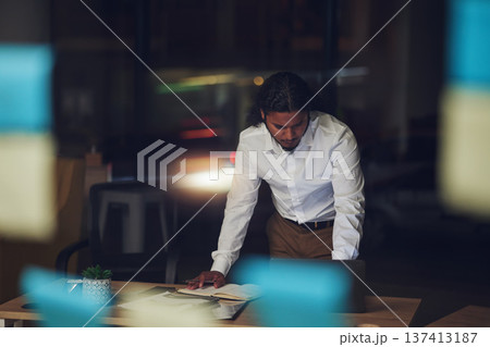 Business man, night and planning in office, documents and reading for proposal, goals or deadline for report. Entrepreneur, paperwork and glass for sticky note, thinking and ideas in dark workplace 137413187
