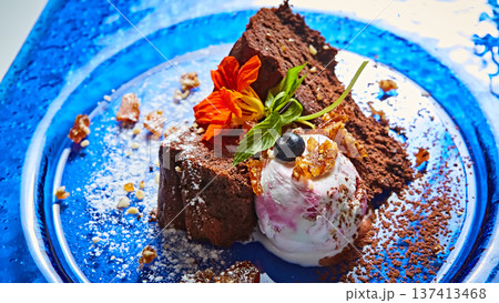 Gourmet chocolate cake served with berry-swirl ice cream and edible flowers 137413468