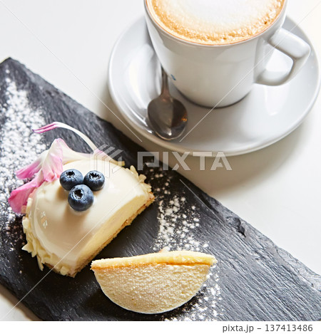 Elegant white chocolate mousse dome dessert topped with fresh blueberries and a floral petal 137413486