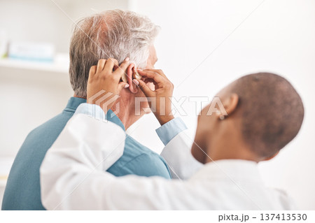 Doctor, helping and man with hearing aid, technology or healthcare or medical device consultation for deaf patient with tinnitus. Listening, test and exam ear tech with nurse or senior male in clinic Doctor, helping and man with hearing aid, technology or healthcare or medical device consultation for deaf patient with tinnitus. Listening, test and exam ear tech with nurse or senior male in clinic 137413530
