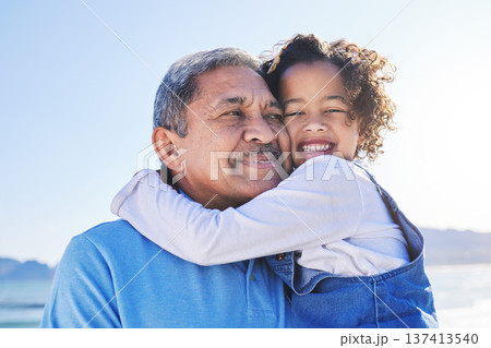 Grandfather, child and happy at the beach for vacation and travel together on outdoor holiday for happiness. Hug, smile and grandparent with kid or young grandchild by the ocean or sea for adventure 137413540