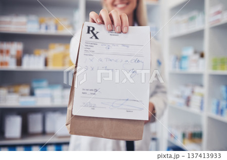 Woman, pharmacist and hand with paper bag for prescription, note or doctor certificate at pharmacy. Closeup of female person or medical professional giving medication or pharmaceutical at drugstore 137413933