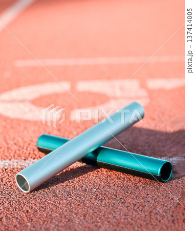 Sports, track and closeup of baton in a stadium for a relay race, marathon or competition. Fitness, running and zoom of athletic equipment on the ground for cardio training, workout or exercise. 137414005