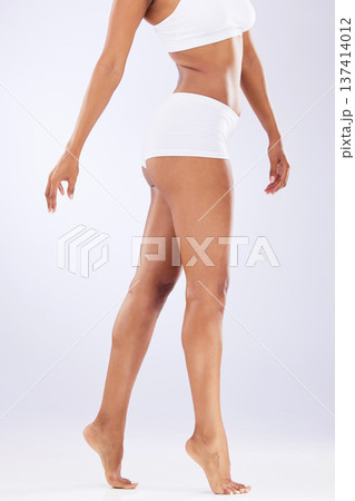 Skincare, body and woman legs with epilation, waxing and dermatology sitting in a studio. White background, laser and hair removal with self care, skin glow and wellness with fitness and model 137414012