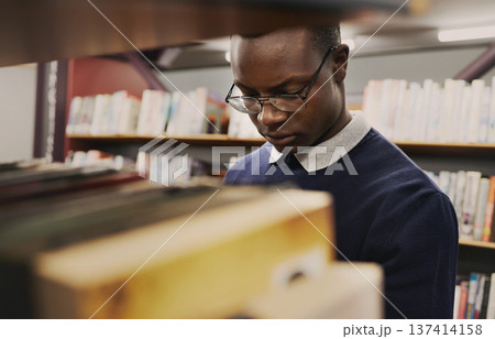 University, student and black man in a library reading and learning on campus for knowledge and education in college. Smart, clever and person doing research with books on a shelf for an exam University, student and black man in a library reading and learning on campus for knowledge and education in college. Smart, clever and person doing research with books on a shelf for an exam 137414158