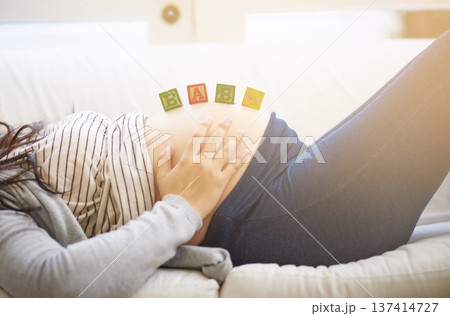 Home, pregnant woman and hands with building blocks, baby announcement or prenatal belly support. Pregnancy news, rest or person with wooden toys on stomach, future parenthood or coming soon message 137414727
