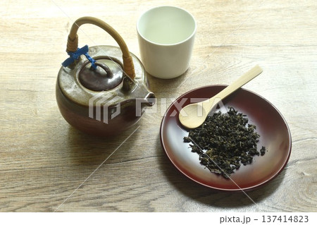 dry Chinese tea leaves and wooden spoon with pottery pot and glass on table dry Chinese tea leaves and wooden spoon with pottery pot and glass on table 137414823