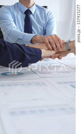Teamwork and business collaboration with colleagues joining hands over financial charts, symbolizing unity, partnership, success, and strategic corporate planning Teamwork and business collaboration with colleagues joining hands over financial charts, symbolizing unity, partnership, success, and strategic corporate planning 137415277