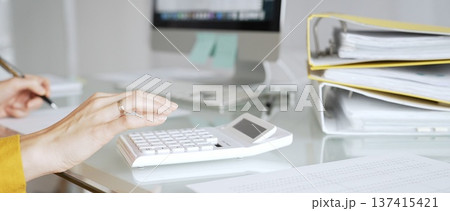 Accountant in yellow blouse working on financial budget, calculating taxes and expenses, managing paperwork in office. Audit and taxes in business Accountant in yellow blouse working on financial budget, calculating taxes and expenses, managing paperwork in office. Audit and taxes in business 137415421
