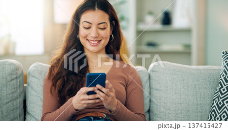 Phone, social media and happy woman texting on a dating app and smiling on the weekend at home on the couch. Smile, chatting and young girl loves typing a message on a social networking website 137415427