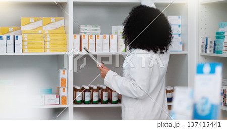 Young and focused pharmacist use her tablet to do stock taking in a modern pharmacy drugstore. Multiethnic female health professional worker or medication expert in a chemist using a digital gadget Young and focused pharmacist use her tablet to do stock taking in a modern pharmacy drugstore. Multiethnic female health professional worker or medication expert in a chemist using a digital gadget 137415441