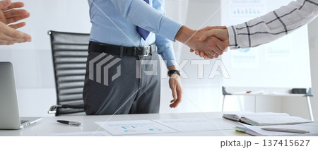 Business partnership success concept with handshake in modern office, financial charts, graphs and laptop on desk representing teamwork, agreement and corporate growth Business partnership success concept with handshake in modern office, financial charts, graphs and laptop on desk representing teamwork, agreement and corporate growth 137415627