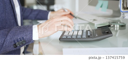 Accountant calculating finances at office desk, person analyzing budget, doing bookkeeping, managing taxes and data. Audit and taxes in business Accountant calculating finances at office desk, person analyzing budget, doing bookkeeping, managing taxes and data. Audit and taxes in business 137415759