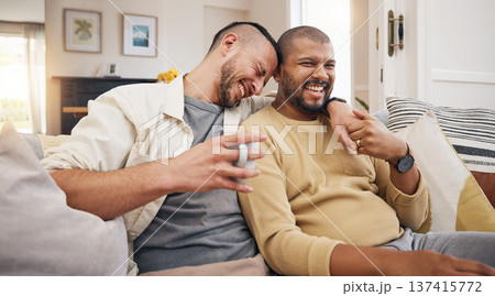 Laughing, relax and a gay couple on the sofa with coffee, conversation or love in a house. Happy, together and lgbt men on the living room couch for a funny story, communication or speaking with tea 137415772
