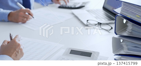 Auditors collaborating in modern office, analyzing financial documents and using calculator with a laptop displaying charts. Audit and taxes in business 137415799