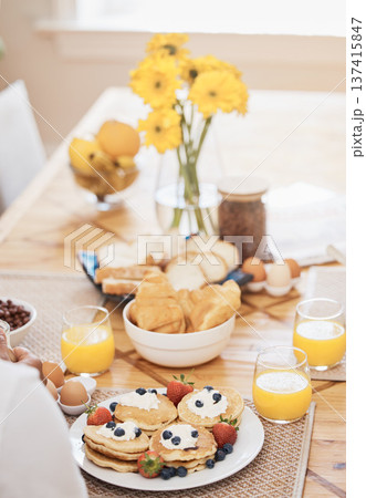 Pancakes, breakfast and orange juice on table in home in the morning. Bread waffle, hands and fruits for eating, healthy diet and strawberry cream in wellness nutrition, blueberry food and egg meal. 137415847
