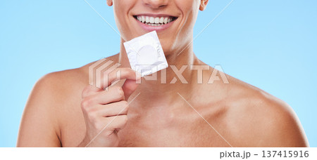 Smile, hand and man with a condom on a blue background for security or birth control in sex. Happy, health and person or guy showing protection or a product for sexual safety choice or contraception Smile, hand and man with a condom on a blue background for security or birth control in sex. Happy, health and person or guy showing protection or a product for sexual safety choice or contraception 137415916