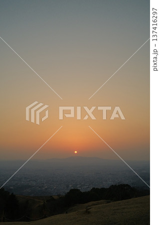 霞んだ空に光が柔らかく拡散する夕日。上部に広いコピースペースがある俯瞰風景 137416297