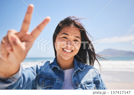 Portrait, woman and sign for peace on beach, holiday or profile picture from vacation in Indonesia on summer or break. Happy, face and smile at the ocean, sea or person travel in nature with freedom 137417147