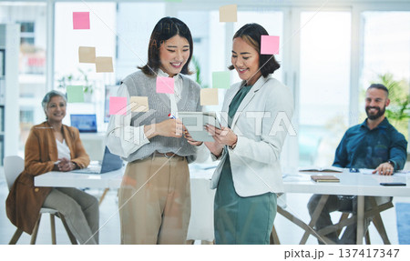 Business women, tablet and teamwork on glass board for marketing, project planning and happy ideas in meeting. Professional people for digital, sticky notes and scrum or agile presentation in office Business women, tablet and teamwork on glass board for marketing, project planning and happy ideas in meeting. Professional people for digital, sticky notes and scrum or agile presentation in office 137417347