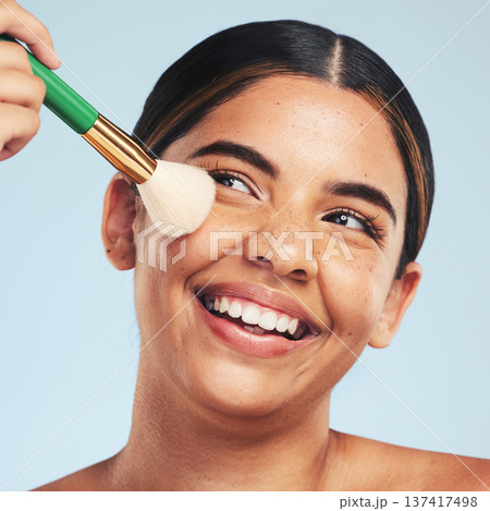 Face, happy woman and brush for makeup in studio to apply foundation for glow on blue background. Model, smile and aesthetic cosmetics for skincare tools, facial beauty powder or thinking of makeover Face, happy woman and brush for makeup in studio to apply foundation for glow on blue background. Model, smile and aesthetic cosmetics for skincare tools, facial beauty powder or thinking of makeover 137417498