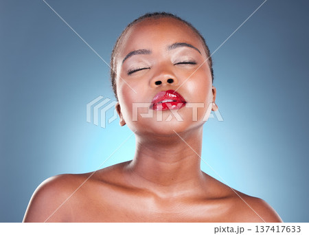 Glow, beauty and black woman with makeup, cosmetics and spa facial on a blue studio background. Shine, African person and model with lip gloss and aesthetic with dermatology, skincare and luxury 137417633