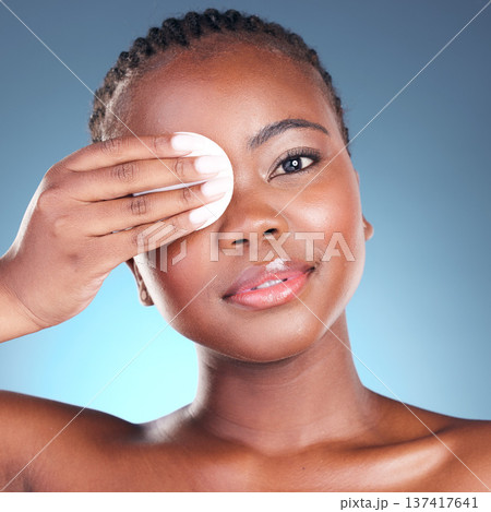 Portrait, beauty and cotton swab with a black woman in studio on a blue background for skincare. Face, hygiene and cosmetics with a young model cleaning her skin for wellness or antiaging care 137417641