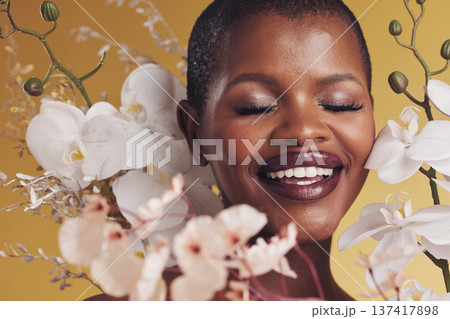 Black woman, flowers and beauty with smile, makeup and natural cosmetics isolated on studio background. African model, orchid and nature, sustainable skincare with eyes closed, facial and glow 137417898